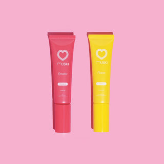 Twee tubes Muski intieme musk: Romantic (aardbei) en Passion (monoï) op roze achtergrond.