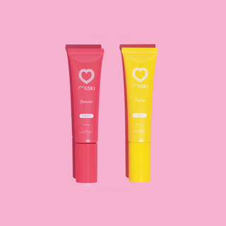Twee tubes Muski intieme musk: Romantic (aardbei) en Passion (monoï) op roze achtergrond.