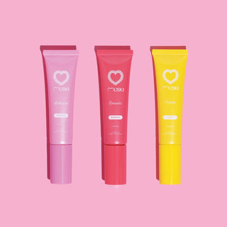 Drie tubes Muski intieme musk: Seduction (witte musk), Romantic (aardbei) en Passion (monoï) op roze achtergrond.