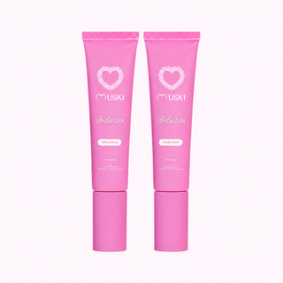 Twee MUSKI Seduction Intieme Musk tubes op een lichtroze achtergrond